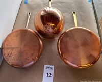 Top view of two copper sauce pans and one copper ladle showing exterior finishes and handles