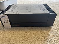 Front view of Hafler DH-220 amplifier showing black metal casing with some dust and wear, heat sinks on sides.