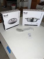 Photo shows Mepra cookware boxes: one with frying pan and one with lid, along with a plastic-wrapped serving spoon.