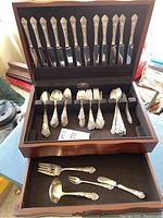 Open wooden chest showing two drawers with top row of twelve knives and bottom compartments of spoons and forks