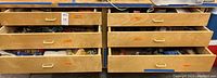 Wooden drawers with multiple compartments labeled for different tool types and containing various tools and parts.