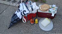 Wide angle photo showing most items including coolers, umbrella, lanterns, food containers, plates, and plate holders