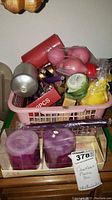Overview photo showing assorted candles in a pink plastic basket as seen from an angle.