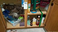 Wood floor care products, feather dusters, microfiber dusters, cleaning supplies arranged in a wooden cabinet.