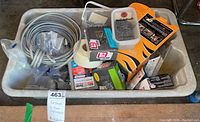 Photo showing plastic tub containing various fasteners including wire, tape, boxes of nails and clips