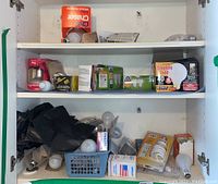 Image showing multiple boxed and loose light bulbs on two shelves inside a cabinet including GE Double Life 40 watt box and several other packagings.