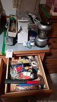 Overview of the lantern, nightlight, hammer, can of polish, and various small utility items in drawer.