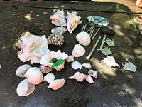 Full view of assorted sea shells and disassembled garden wind chime parts on a dark surface