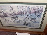 Framed wall art print showing wolves among birch trees in winter, colors white, blue, green, multi-layered mat in green and cream, framed