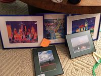 Five framed pieces of various Seattle and Pacific Northwest themed paintings and photographs on carpet