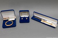 Full set including hinged bangle, clip-on earrings, and wristwatch displayed with original blue velvet boxes.