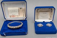 Pair of earrings and hinged bangle displayed in original blue velvet boxes with certificates of authenticity inside the lids.