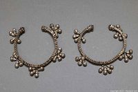 Pair of East Indian style silver cuff bangles displayed on grey background showing overall design and shape.