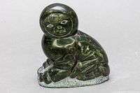 Front angle view of signed Inuit stone carving figure in dark green stone with detailed facial features and attire.