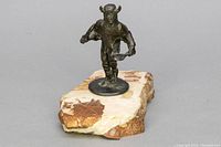 Front view of bronze Native American Chief sculpture mounted on polished stone base, showcasing figure in mid-dance with horned headdress.