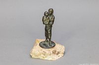 Front and side view of bronze mother and child sculpture on light stone base.