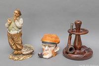 Three collectible items: A. Borosot ceramic figurine smoking pipe man, carved pipe head, vintage wooden Dunhill pipe holder with two pipes