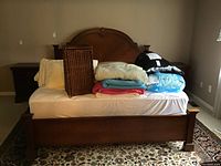 King size wooden bed frame with curved headboard displaying carved detail and footboard with fluted post detail.