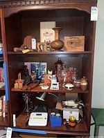 Photo showing wooden gavels, a ceramic vase, wooden bookends, and various glass candy dishes on shelves.