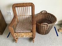 Child size wicker rocking chair with cushion placed next to large wicker basket