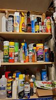 Multiple shelves packed with various aerosols, bottles, and containers of cleaners, insecticides, lubricants, polishes, and other chemicals.