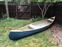 Full side view of blue Old Town canoe on grass