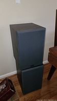 Two Yamaha speakers stacked on top of each other showing front grille and wood grain finish on sides.
