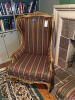 High back wing chair with carved wood trim and striped upholstery