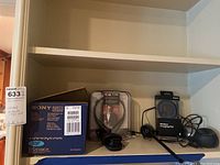 Sony Handycam DCR-DVD301 box, LG stereo headset packaged, Samsung wireless charging pad with cable on shelf