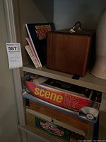 Shelf showing the wooden Mah Jong box, Scene It? DVD game, and Monopoly board game, stacked with visible labels and packaging.