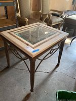 Photo showing the full square table with marble top and glass center insert on metal frame with decorative sides.