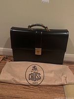 Front view of black leather briefcase and beige dust bag