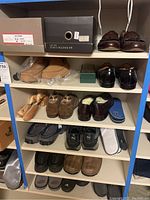 Full shelf view showing multiple pairs of men's shoes of various styles and sizes with some boxed.