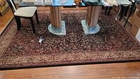 Full view of the Shaw area rug under a glass-top table, showing the overall floral design and border.