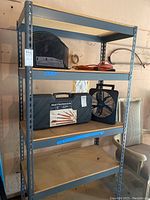 Front view of metal shelving unit with particleboard shelves, includes some items on shelves for scale but not part of the lot.