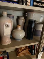 Shelf with seven varying pottery pieces, showing different shapes and glaze colors