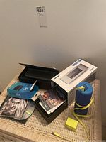 Overview shot of Bose Mini Link speaker, Echo Dot box, CDs and charger on wicker table.