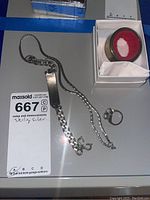 Overview photo showing all four items: silver bracelet, chain necklace, ring, and wine stopper in box.
