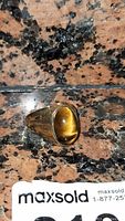 Top-down view of ring showing oval tiger’s eye cabochon set in metal band.