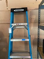 Front view of the Werner 6ft metal step ladder with visible blue frame, silver steps and black top cap with Werner logo.