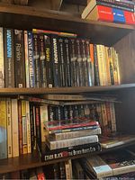 Books arranged on wooden shelves including novels by Ian Rankin, Lawrence Block, and others. Various colors and conditions, mostly paperbacks and some hardcovers.
