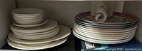 Various stacked white plates and bowls with a subtle texture