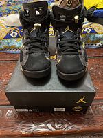 Front view of black Air Jordan 6 sneakers with floral embroidery on box lid, showing the lace locks and toe area.