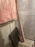 Metal gate panels leaning against wall with wood and copper pipe nearby