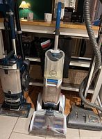 Front view of two upright vacuum cleaner units with visible dust and wear