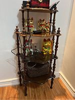 Full view of wooden shelving unit in corner with various decorative items on shelves showing overall structure and condition.