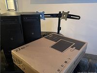 Boxed Acer 22-inch widescreen monitor and adjustable dual monitor mounts behind the box mounted on a stand