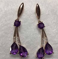 Front view showing both earrings with two pear-shaped amethyst stones and round amethyst on top with white CZ accents on rose gold bars