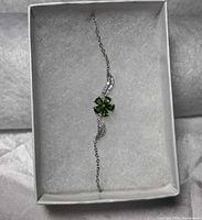 Flower bracelet with green pear cut Chrome Diopside stones and white CZ set in 14k white gold plated 925 sterling silver, displayed in a box.