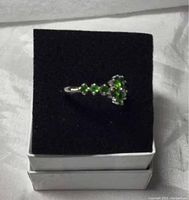 Top angled view of green Chrome Diopside flower ring in box, showing pear cut stones and band detail.